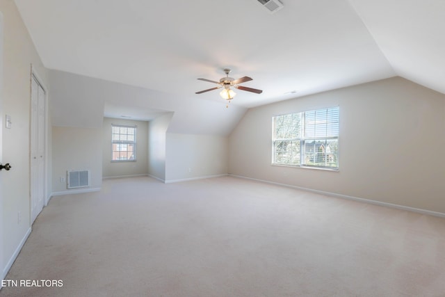 additional living space featuring visible vents, vaulted ceiling, a ceiling fan, and light carpet