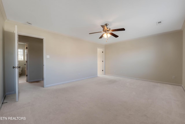spare room with baseboards, ceiling fan, crown molding, and light carpet