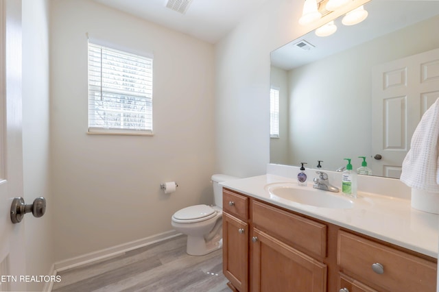 bathroom with visible vents, wood finished floors, toilet, and vanity
