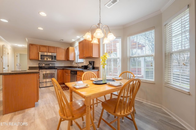 dining area with crown molding, light wood-type flooring, baseboards, a chandelier, and visible vents