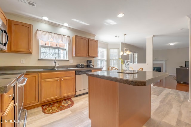 kitchen with ornamental molding, stainless steel appliances, a kitchen island, a sink, and visible vents