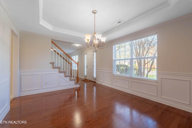 foyer entrance with a tray ceiling, visible vents, hardwood / wood-style floors, and a chandelier