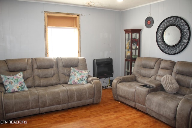 living area with crown molding, light wood-style flooring, and heating unit