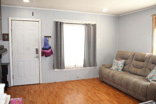 living area with a healthy amount of sunlight, crown molding, and wood finished floors