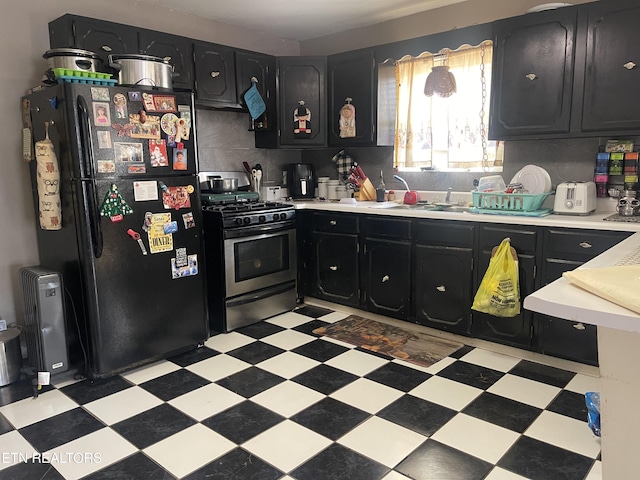 kitchen featuring light floors, freestanding refrigerator, and stainless steel gas range oven