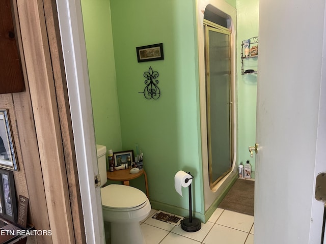 bathroom featuring tile patterned floors, toilet, baseboards, and a stall shower