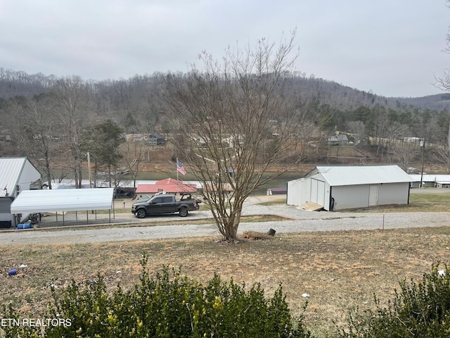 view of yard with an outbuilding, a wooded view, and a mountain view