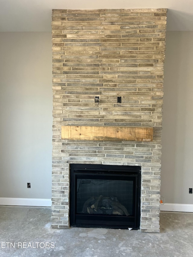 room details featuring unfinished concrete floors, baseboards, and a fireplace