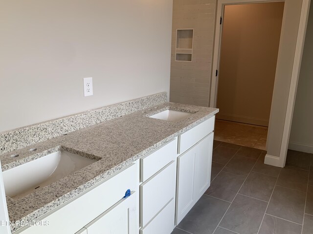 full bathroom featuring tile patterned floors, baseboards, double vanity, and a sink