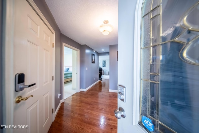 entrance foyer featuring baseboards, a textured ceiling, and wood finished floors