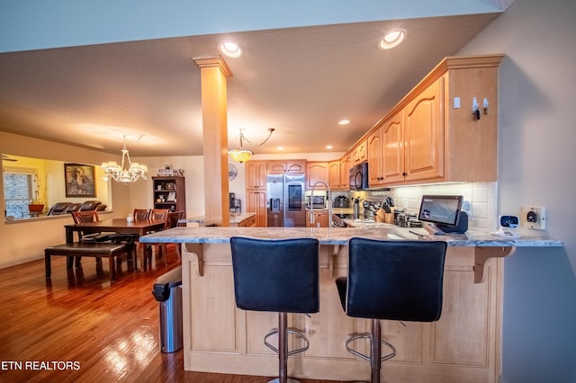 kitchen featuring light brown cabinets, black microwave, stainless steel fridge with ice dispenser, wood finished floors, and range