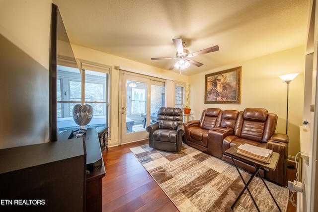 living room featuring a textured ceiling, dark wood-type flooring, and a ceiling fan