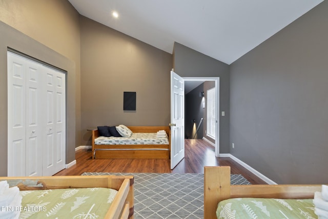 bedroom featuring a closet, wood finished floors, baseboards, and vaulted ceiling
