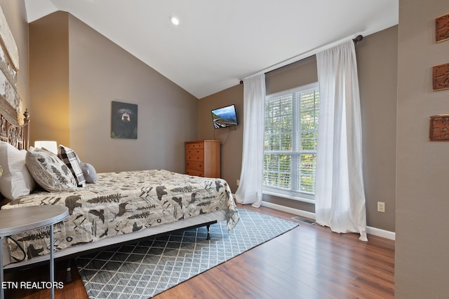bedroom featuring lofted ceiling, wood finished floors, visible vents, and baseboards
