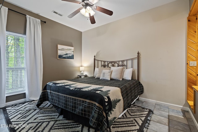bedroom featuring visible vents, baseboards, stone tile flooring, and a ceiling fan