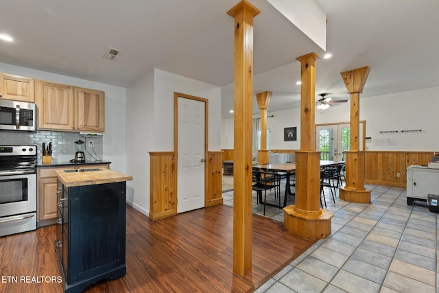 kitchen with butcher block countertops, backsplash, appliances with stainless steel finishes, wainscoting, and ornate columns