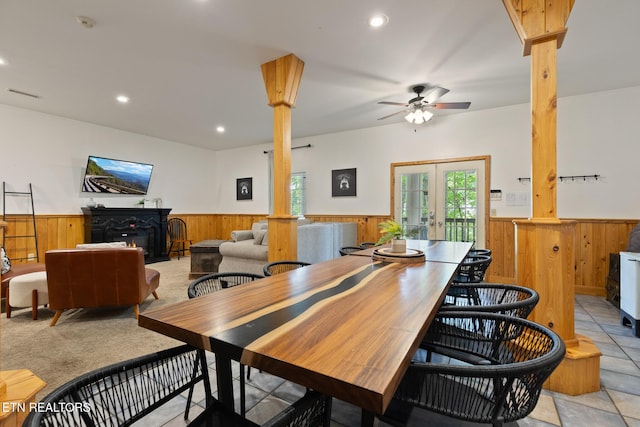 dining room with wooden walls, decorative columns, and a wainscoted wall