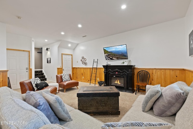carpeted living room with recessed lighting, wooden walls, wainscoting, lofted ceiling, and stairs