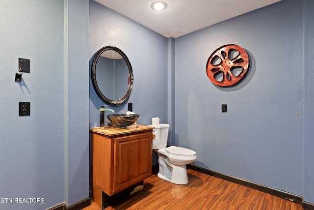 bathroom featuring toilet, wood finished floors, baseboards, and a sink