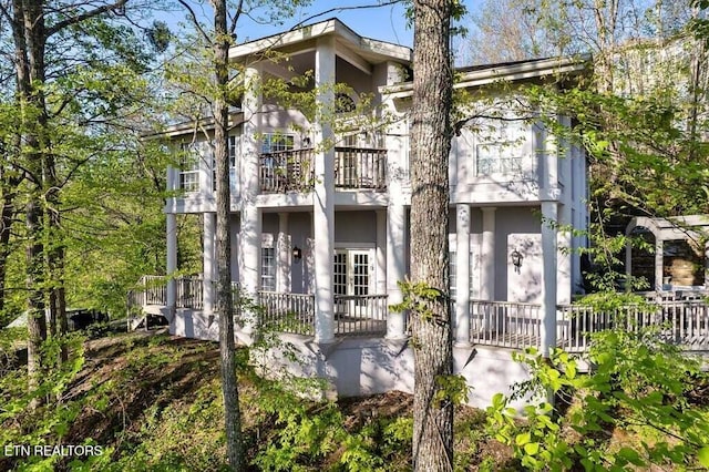 view of front of home with covered porch, stucco siding, and a balcony