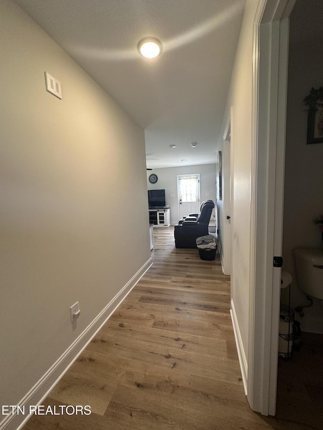 corridor with wood finished floors and baseboards