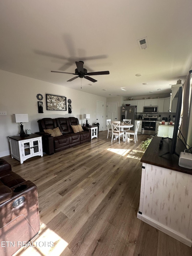living room featuring a ceiling fan, dark wood-style floors, and visible vents