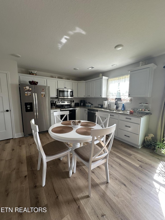 dining space with light wood-type flooring and a textured ceiling