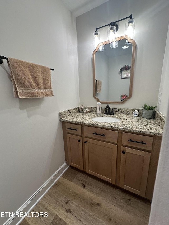 bathroom featuring vanity, baseboards, and wood finished floors