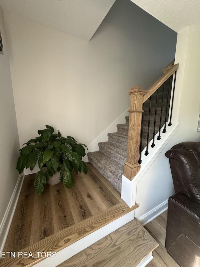 stairway with wood finished floors and baseboards