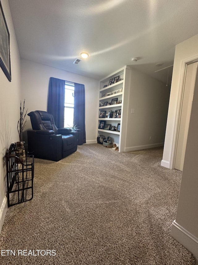 living area with attic access, carpet, visible vents, and baseboards