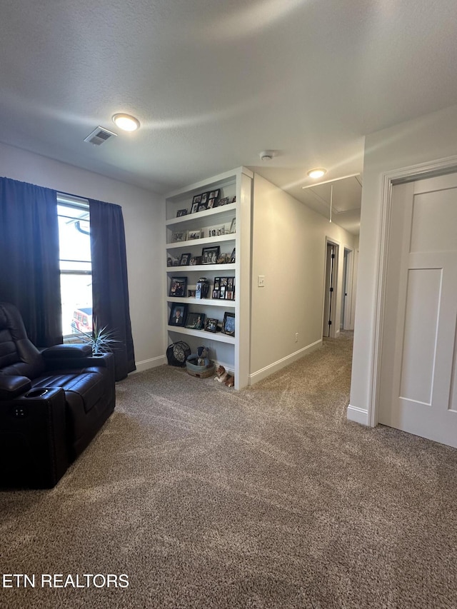 living area with visible vents, attic access, baseboards, and carpet floors