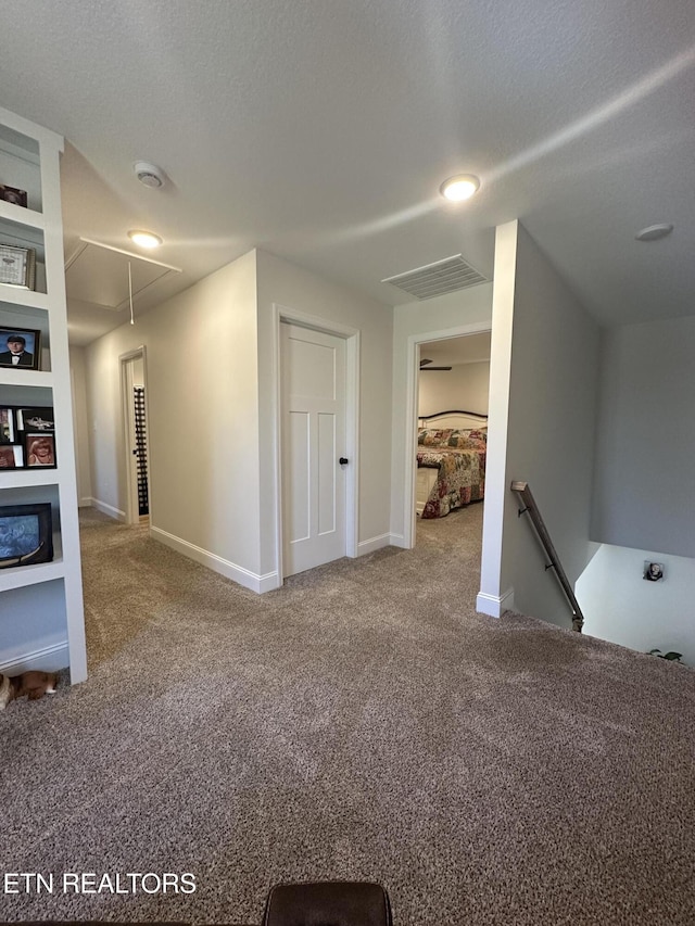 interior space featuring baseboards, visible vents, a textured ceiling, and carpet