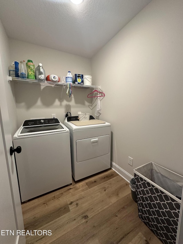 clothes washing area with laundry area, independent washer and dryer, baseboards, and wood finished floors