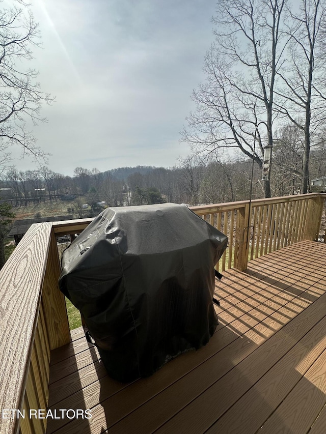 wooden deck with area for grilling and a wooded view