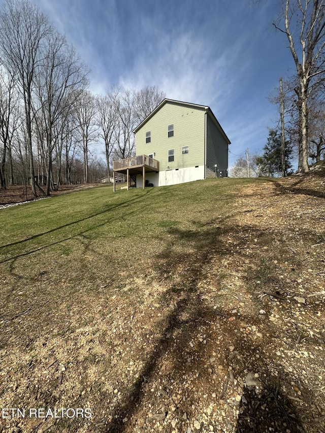 view of side of property with crawl space, a lawn, and a wooden deck