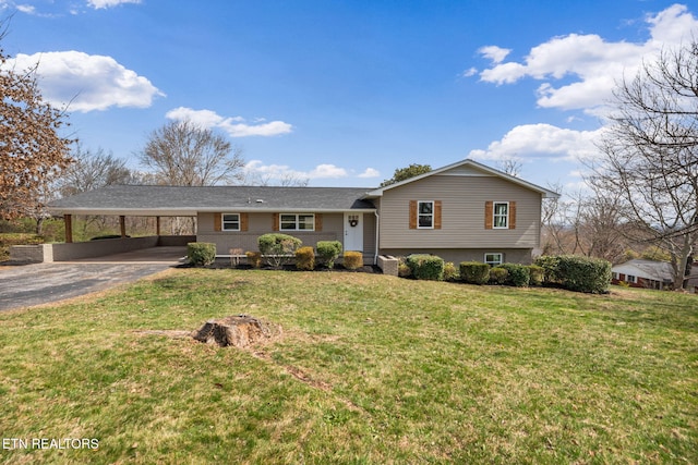 split level home featuring aphalt driveway, an attached carport, brick siding, and a front yard