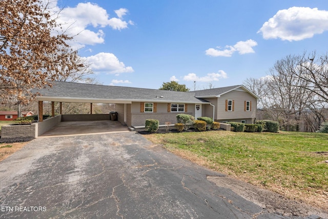 tri-level home featuring an attached carport, a front lawn, and driveway