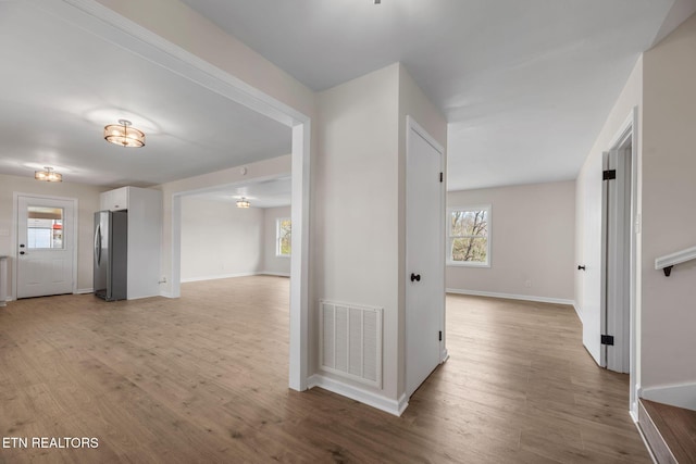 hallway featuring visible vents, a healthy amount of sunlight, and wood finished floors