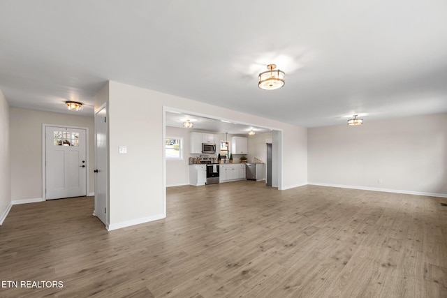 unfurnished living room with baseboards and light wood-style flooring