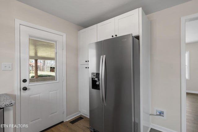 kitchen with visible vents, dark wood-type flooring, white cabinetry, stainless steel fridge, and light stone countertops