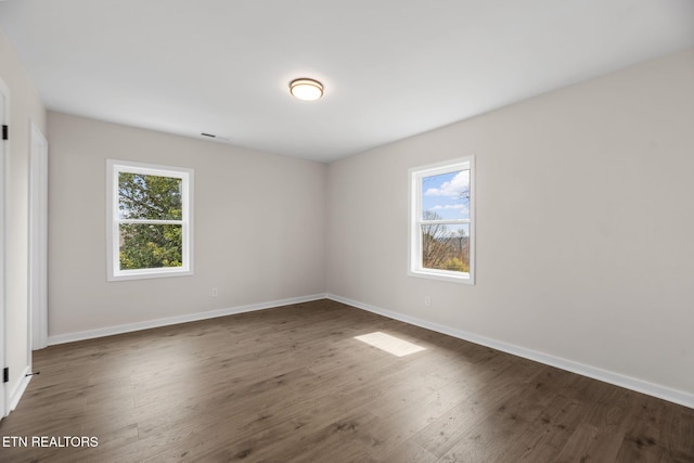 unfurnished room with plenty of natural light, baseboards, and wood finished floors