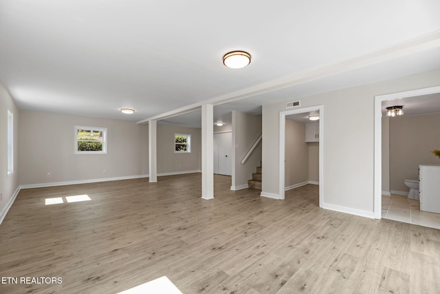 basement featuring stairs, light wood-style floors, visible vents, and baseboards