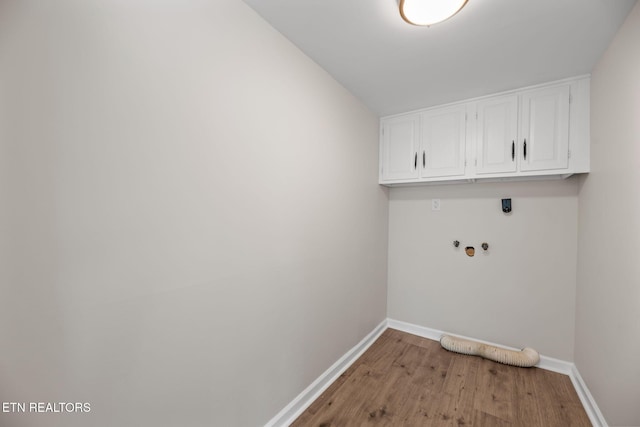 clothes washing area featuring cabinet space, hookup for an electric dryer, baseboards, and wood finished floors