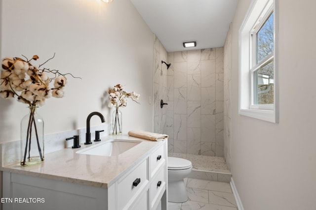 bathroom featuring a tile shower, marble finish floor, toilet, and baseboards