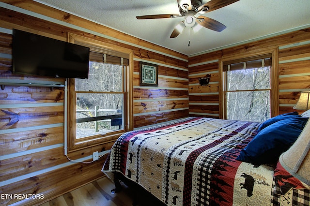 940 Stans Rd, Gatlinburg, TN 37738 - bedroom featuring wood walls, a textured ceiling, wood finished floors, and multiple windows