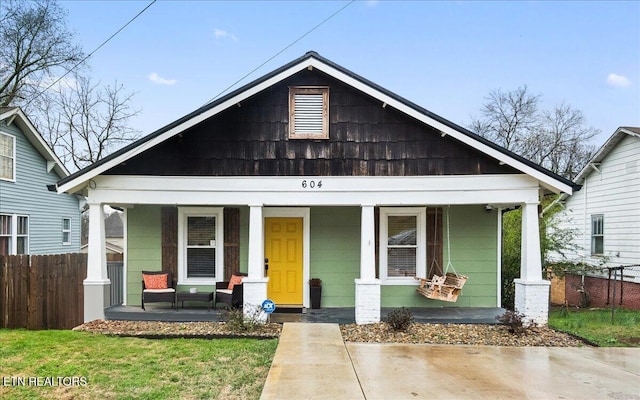 bungalow-style house with a porch and fence