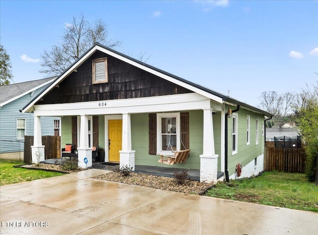 bungalow-style home with covered porch and fence