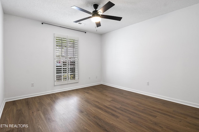 empty room with a textured ceiling, dark wood-style flooring, ceiling fan, and baseboards