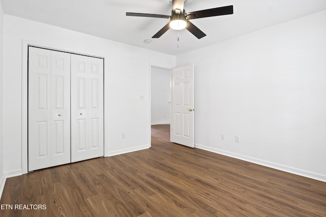 unfurnished bedroom featuring ceiling fan, a closet, dark wood-style flooring, and baseboards