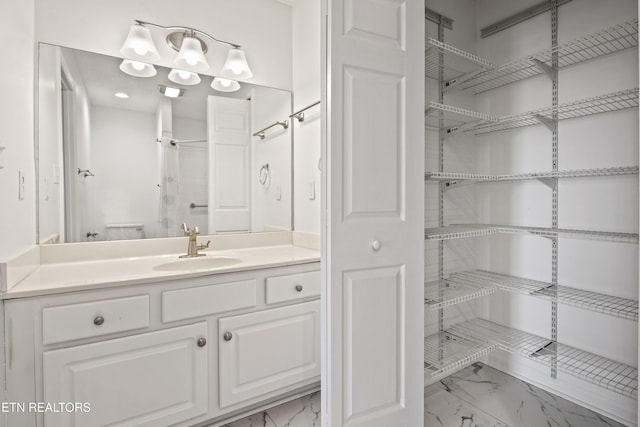 bathroom with toilet, marble finish floor, and vanity